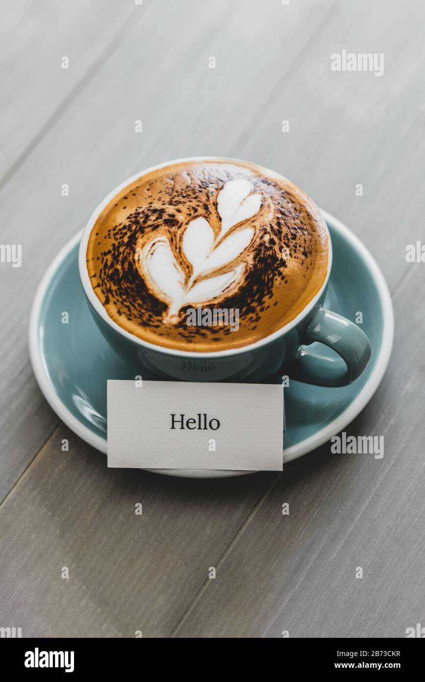 Tasse de café à l'art latte et texte de salutation Hello sur la table en bois vintage dans le café Banque D'Images