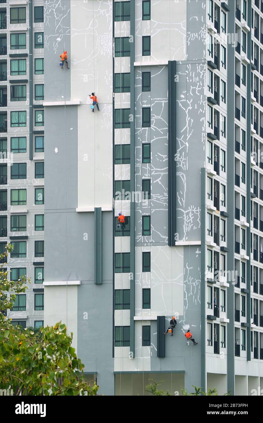 Cinq travailleurs de l'escalade industrielle peignent la façade d'un bâtiment résidentiel haut Banque D'Images