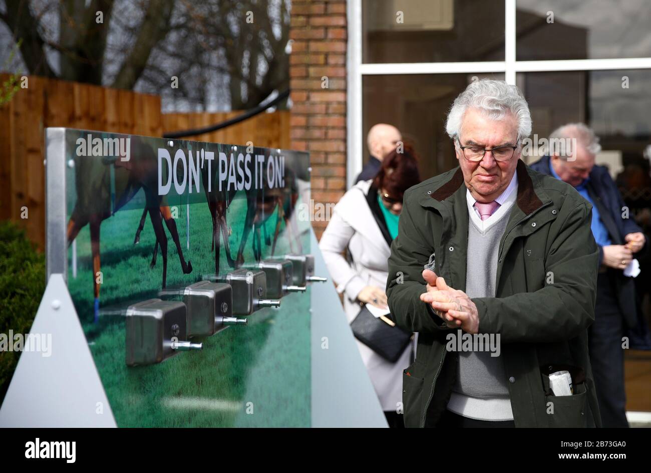 Les racegotiers utilisant des distributeurs de désinfectant pour les mains en raison de l'éclosion de coronavirus au cours du quatrième jour du Cheltenham Festival à l'hippodrome de Cheltenham. Banque D'Images