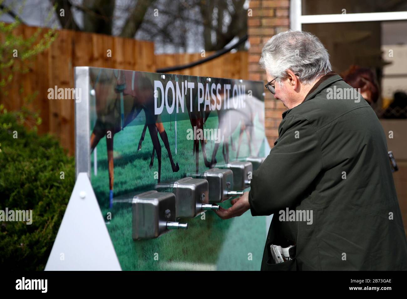 Les racegotiers utilisant des distributeurs de désinfectant pour les mains en raison de l'éclosion de coronavirus au cours du quatrième jour du Cheltenham Festival à l'hippodrome de Cheltenham. Banque D'Images