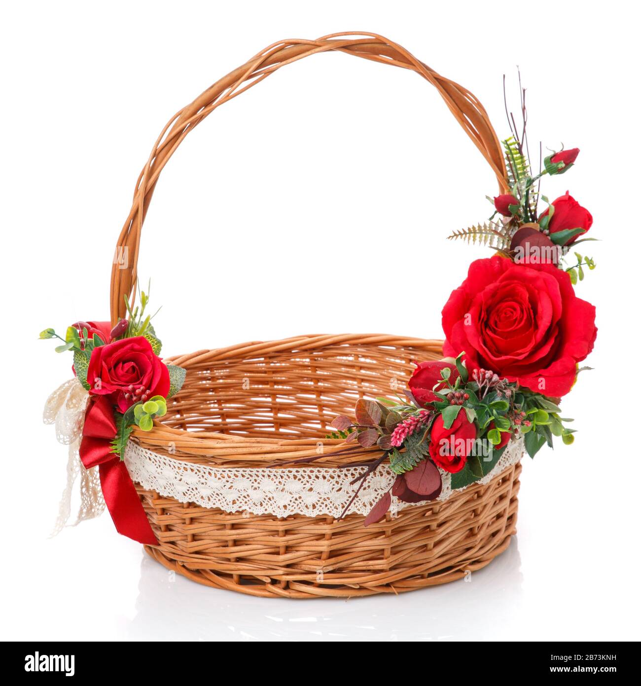 Panier en vigne naturel décoré avec poignée haute. Décor de roses rouges et ruban en dentelle sur fond blanc Banque D'Images