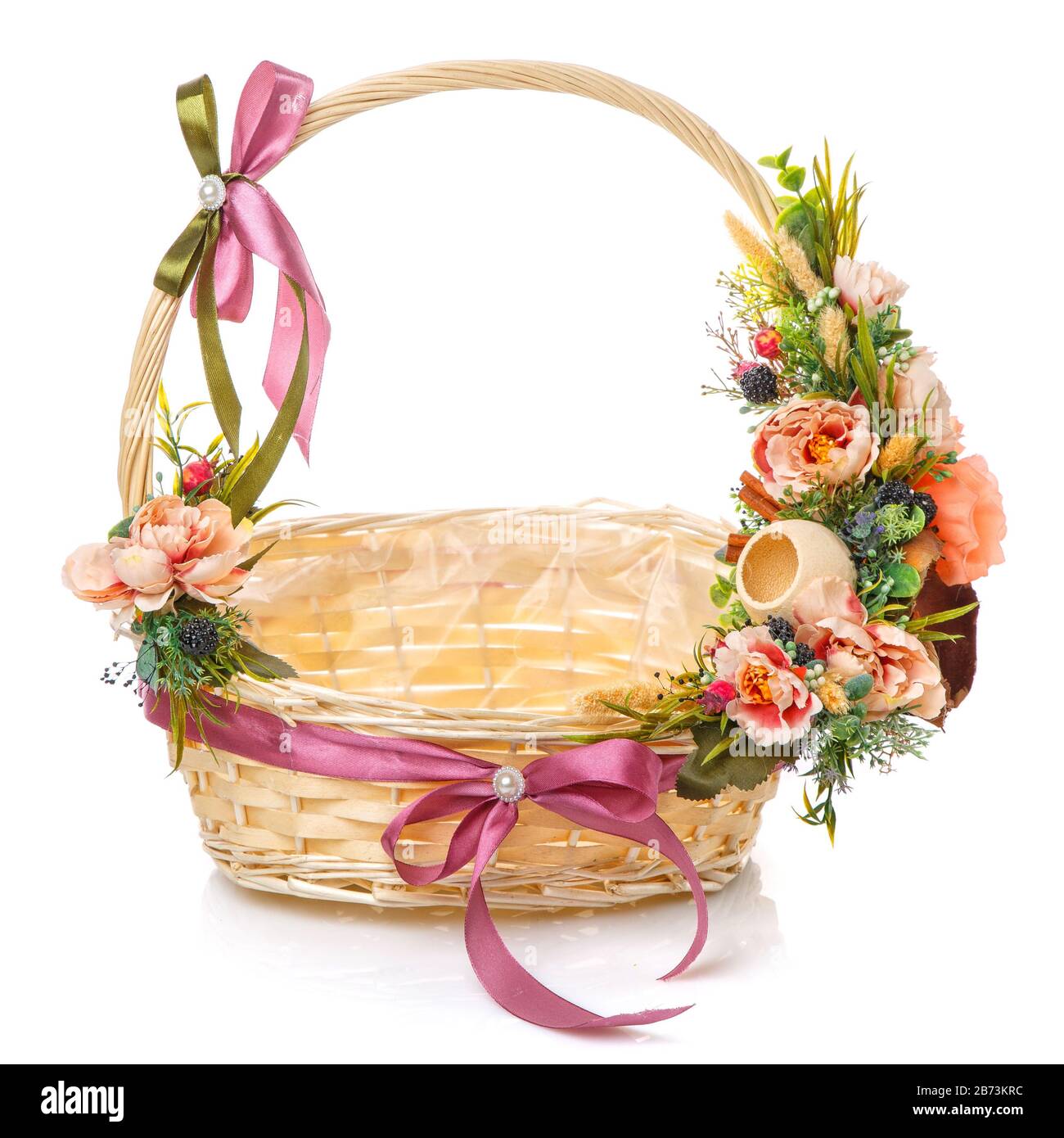 Panier en osier décoré de fleurs roses et d'herbes avec des additifs naturels sur fond blanc Banque D'Images