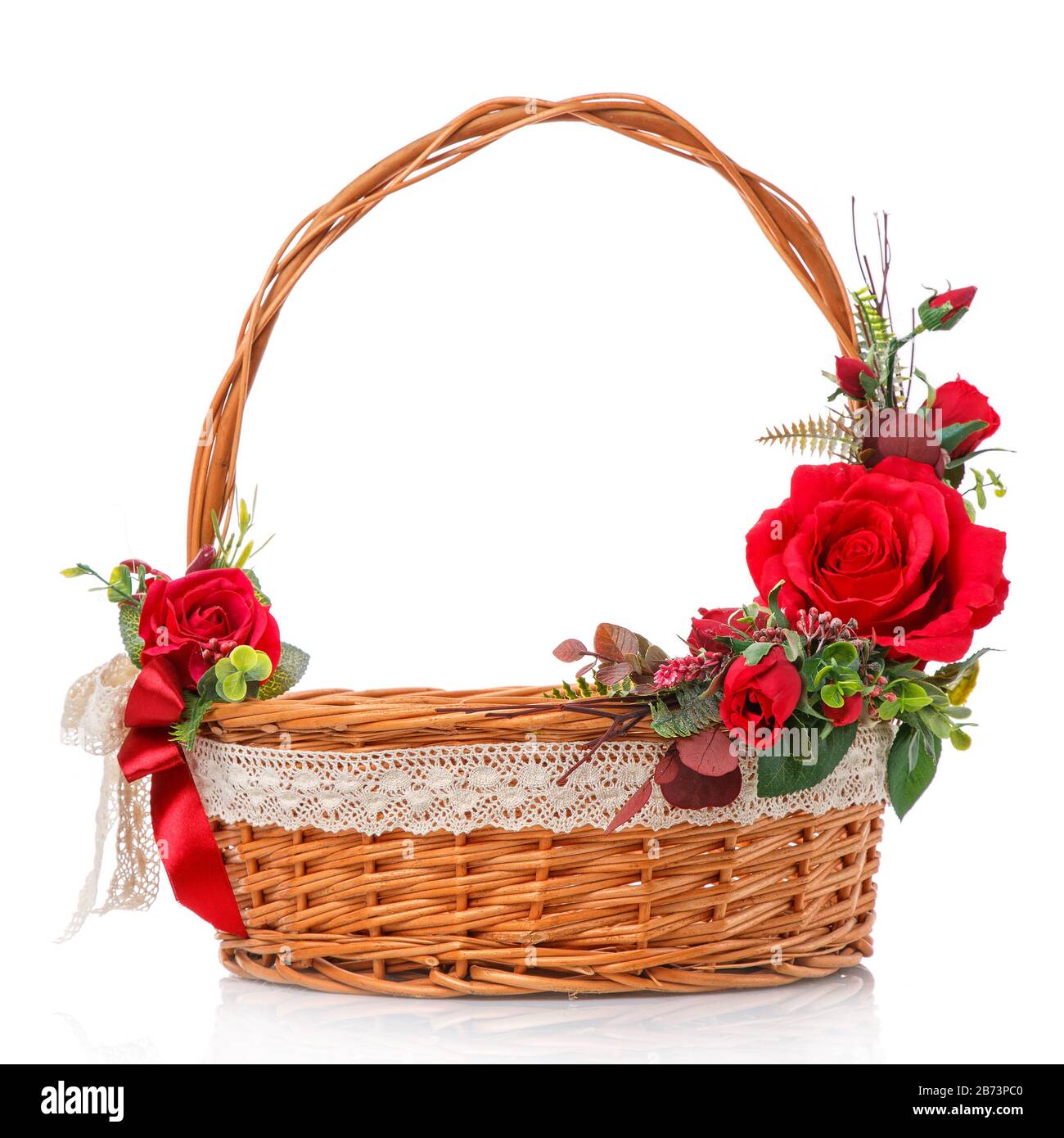 Panier en vigne naturel décoré avec poignée haute. Décor de roses rouges et ruban en dentelle sur fond blanc Banque D'Images