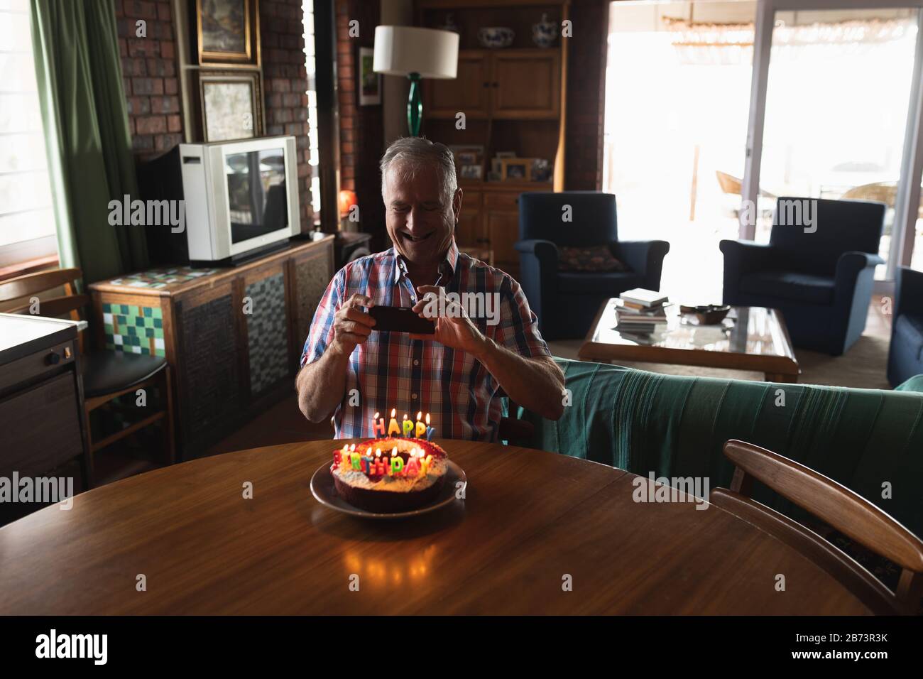 Homme senior prenant photo de son gâteau d'anniversaire Banque D'Images