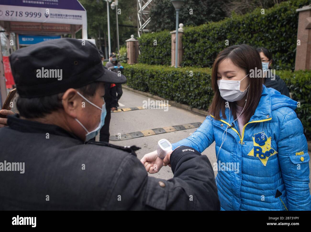 (200313) -- WUHAN, 13 mars 2020 (Xinhua) -- Li Jing (R) a vérifié la température corporelle avant d'entrer dans sa communauté à Wuhan, dans la province de Hubei en Chine centrale, 12 mars 2020. Après avoir subi une quarantaine de 14 jours pour une observation médicale supplémentaire en tant que patient traité COVID-19, l'illustrateur Li Jing et les 84 autres patients ont été autorisés à rentrer chez eux à partir d'une station de traitement médical établie à Wuhan Vocational College of Software and Engineering. (Xinhua/Xiao Yijiu) Banque D'Images