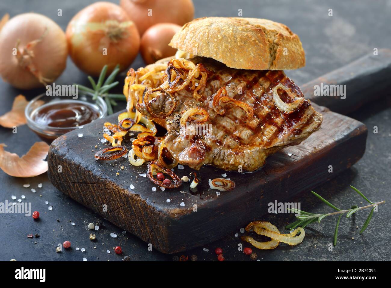 Gros sandwich à la viande : steak de filet de bœuf grillé avec rondelles d'oignons frits sur un rouleau frais Banque D'Images