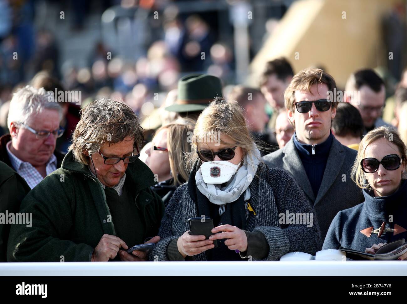 Un Spectator dans les stands portant un masque à la suite de l'éclosion de coronavirus au cours du quatrième jour du Cheltenham Festival à l'hippodrome de Cheltenham. Banque D'Images