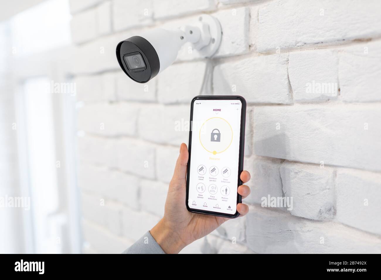 Contrôle de la surveillance vidéo et de l'alarme à domicile avec une application mobile, gros plan sur un smartphone avec une application lancée. Concept de systèmes de sécurité domestique sans fil Banque D'Images