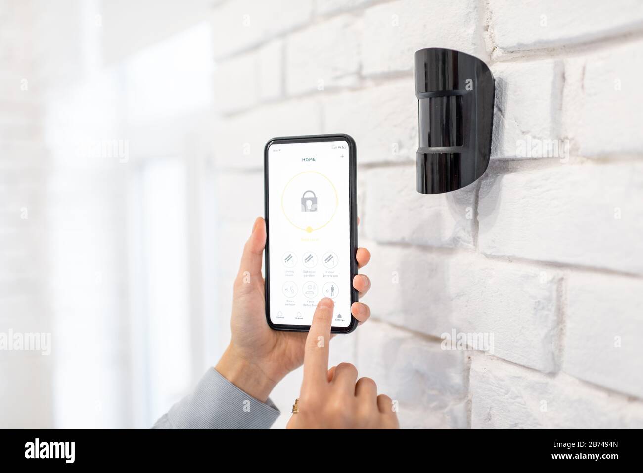 Contrôle du système d'alarme avec smartphone et application mobile spéciale sans fil, en tenant le capteur de mouvement à l'intérieur de l'appareil Banque D'Images