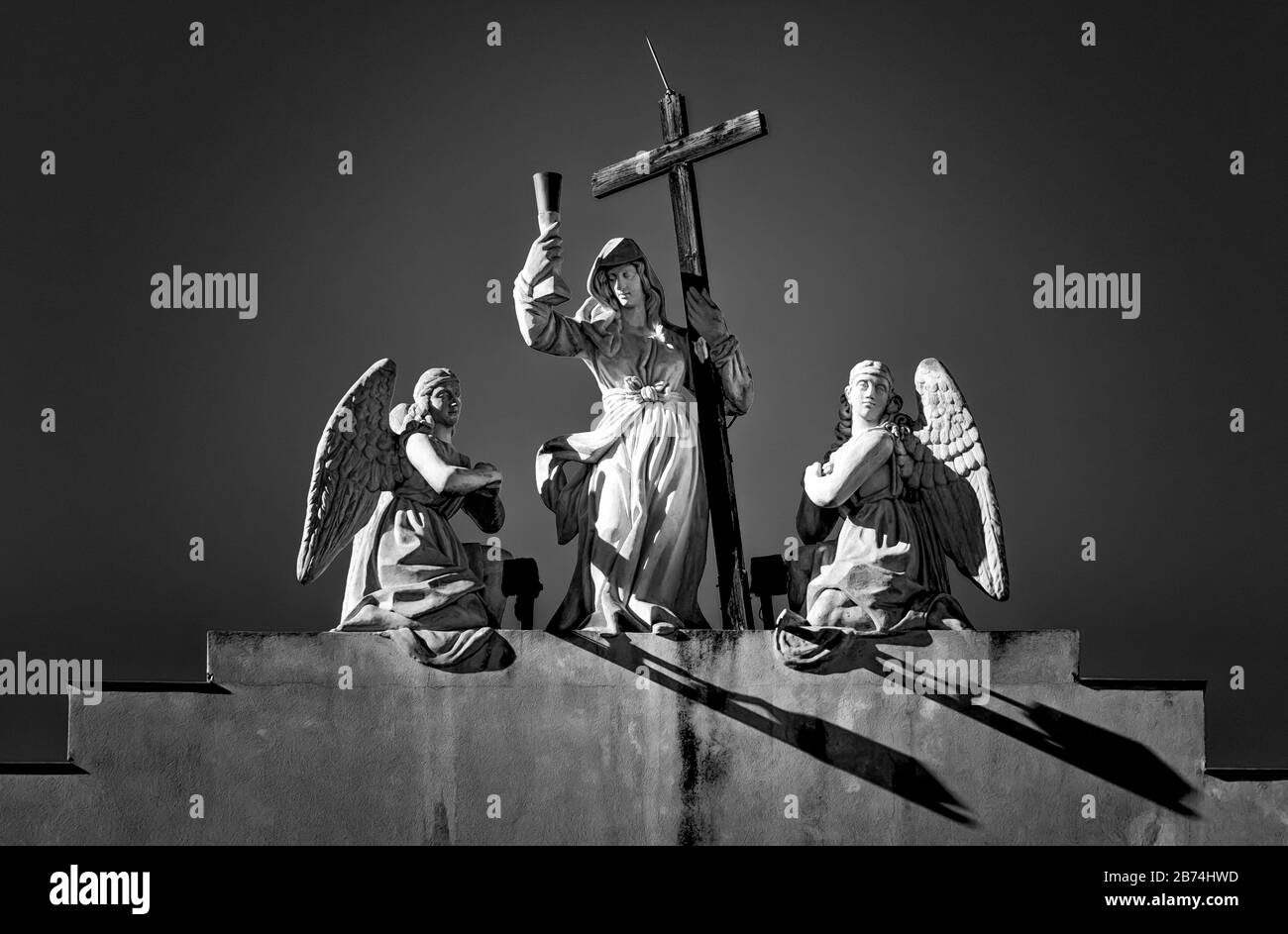 Cliché en niveaux de gris de statues de trois anges tenant le Christin croix Banque D'Images