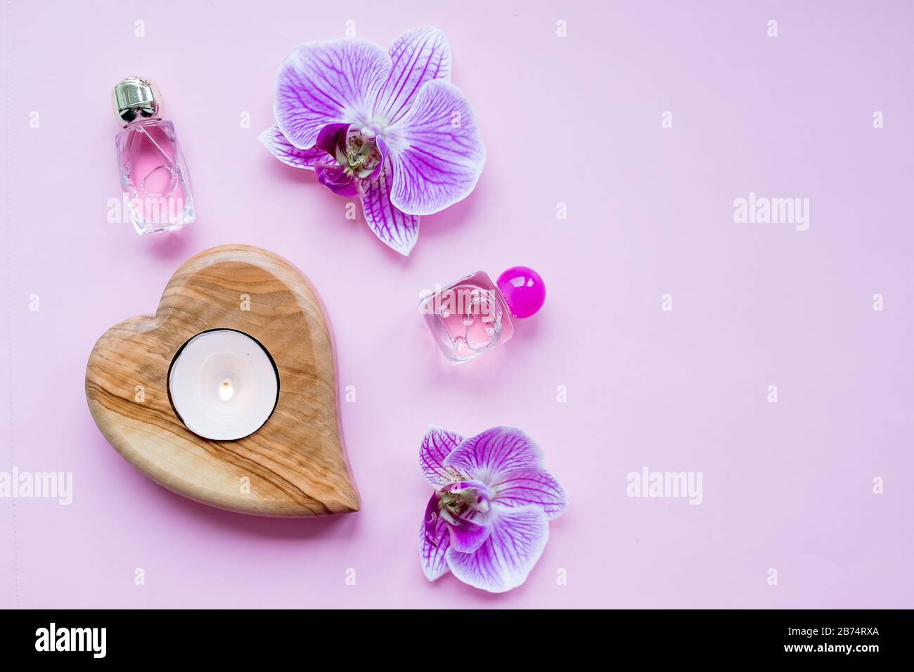 Concept de blog de beauté. Accessoires, fleurs, cosmétiques et bougie sur fond rose, copyspace. Concept Day pour Femme. Banque D'Images