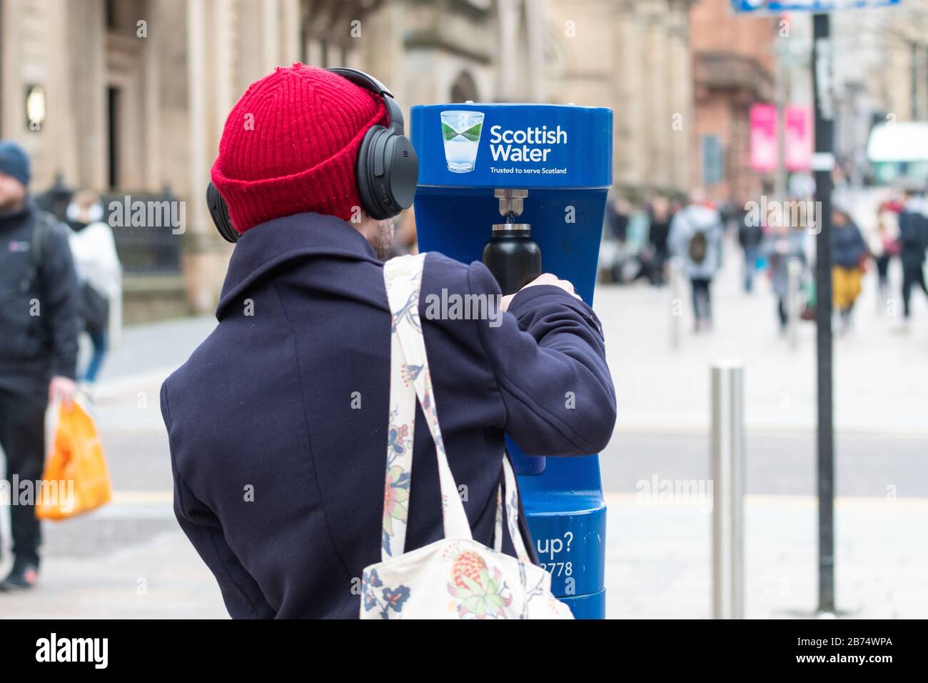 Personne utilisant le point de remplissage d'eau public - Scottish Water Top Tap - Buchanan Street, centre-ville de Glasgow, Ecosse, Royaume-Uni Banque D'Images