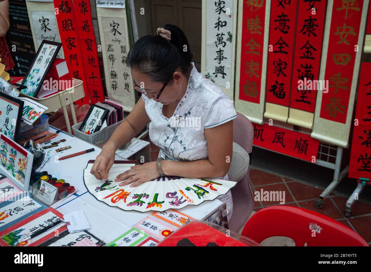 17.01.2020, Singapour, République de Singapour, Asie - l'artiste Jessie Ren écrit des fans, des bannières et des rouleaux avec des félicitations et des bénédictions individuelles pour le nouvel an chinois à venir sous la forme de calligraphie chinoise peignée à la main dans un stand de rue dans le quartier de Chinatown. [traduction automatique] Banque D'Images