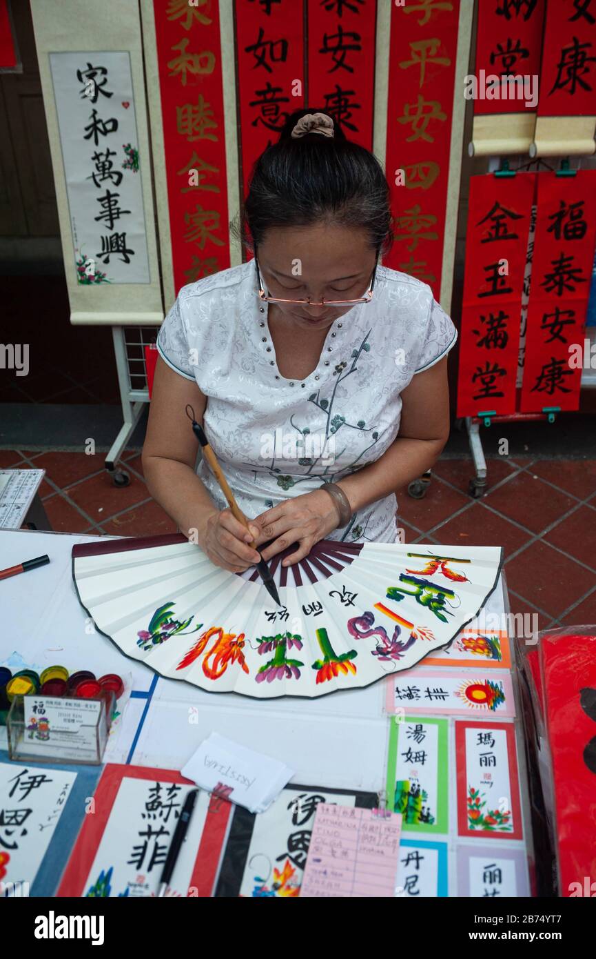 17.01.2020, Singapour, République de Singapour, Asie - l'artiste Jessie Ren écrit des fans, des bannières et des rouleaux avec des félicitations et des bénédictions individuelles pour le nouvel an chinois à venir sous la forme de calligraphie chinoise peignée à la main dans un stand de rue dans le quartier de Chinatown. [traduction automatique] Banque D'Images