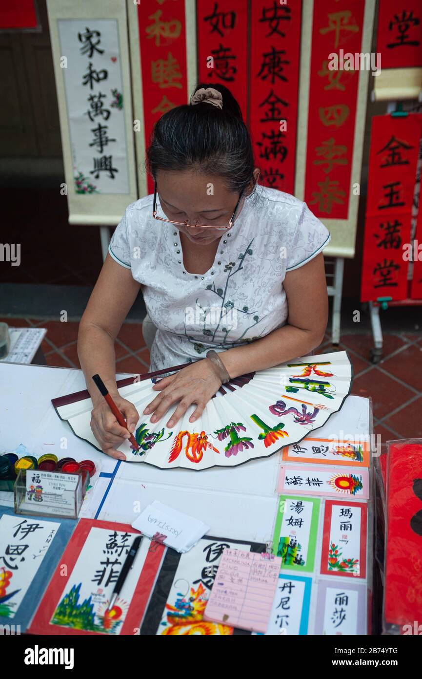 17.01.2020, Singapour, République de Singapour, Asie - l'artiste Jessie Ren écrit des fans, des bannières et des rouleaux avec des félicitations et des bénédictions individuelles pour le nouvel an chinois à venir sous la forme de calligraphie chinoise peignée à la main dans un stand de rue dans le quartier de Chinatown. [traduction automatique] Banque D'Images