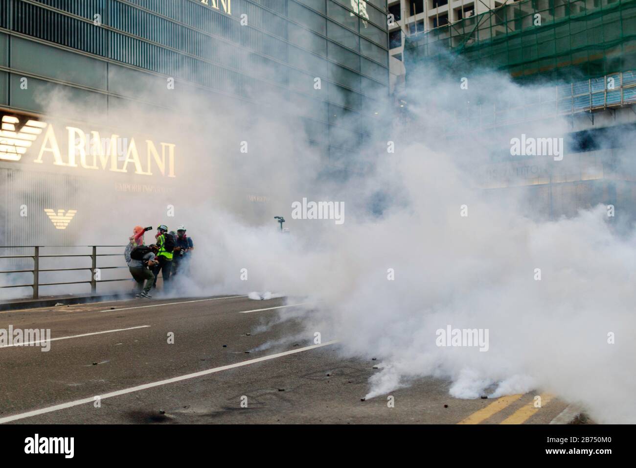 Les journalistes se déplacent au milieu du gaz lacrymogène tiré par la police. Les manifestants bloquent le quartier central, le principal quartier financier de Hong Kong après que la police a abattu un enfant le 11 novembre 2019. Banque D'Images