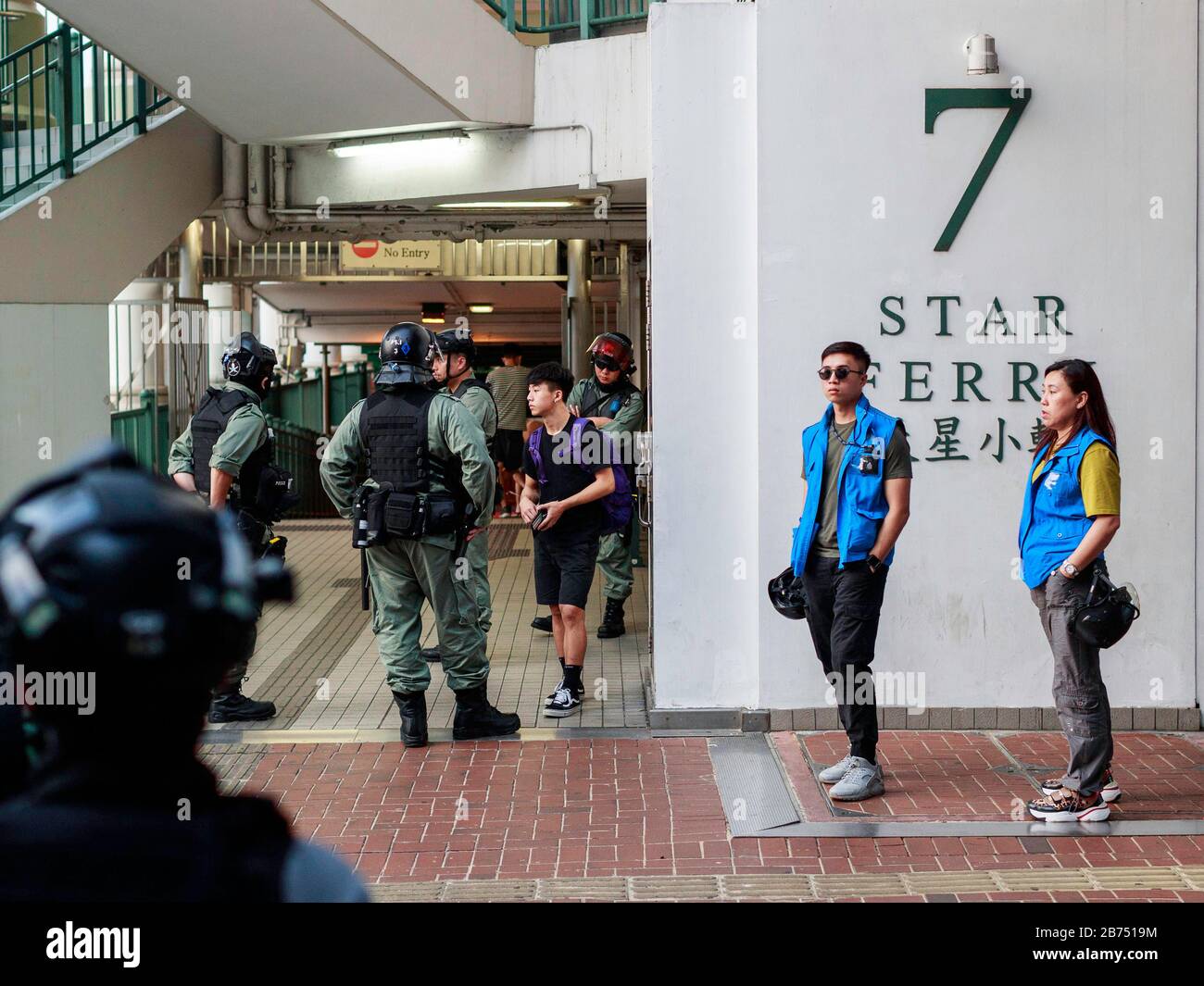Arrêt de la police et recherche d'un jeune homme à l'embarcadère Star Ferry de l'île de Hong Kong. Les manifestants anti-gouvernementaux s'opposent à la police à Tsim Sha Tsui lors d'un rassemblement. La police utilise plus tard du gaz lacrymogène, du spray au poivre et du canon à eau pour disperser la foule. Banque D'Images