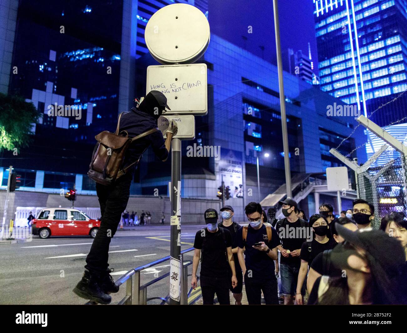 Un protester écrit "Hong Kong n'est pas la Chine" sur un poteau. Les manifestants se confrontent avec la police au cinquième anniversaire du mouvement des parapluies de l'Amirauté. La police utilise un canon à eau pour les disperser. Banque D'Images