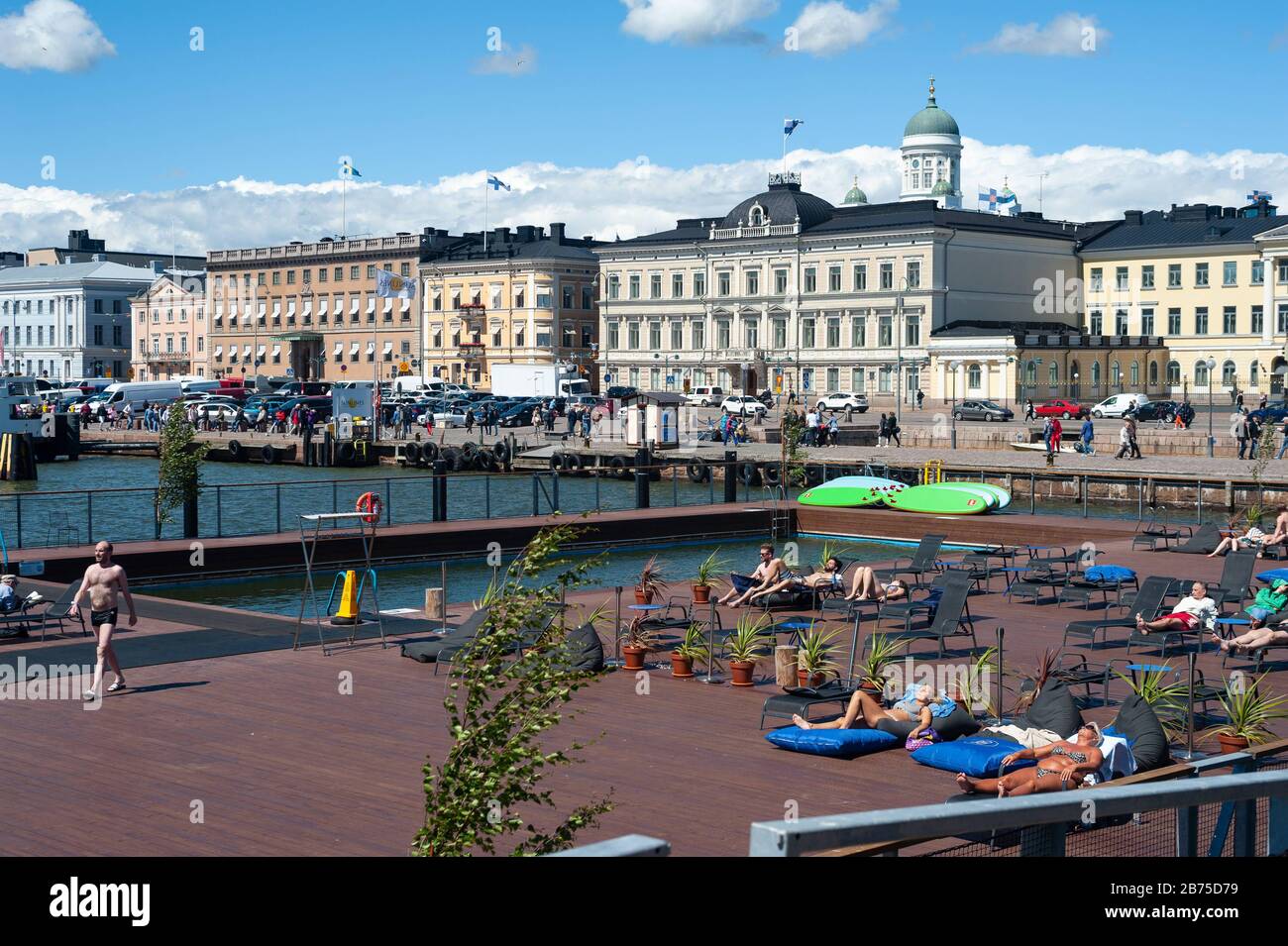 23.06.2018 - Helsinki, Finlande, Europe - les visiteurs bronzer sur la terrasse ensoleillée de la piscine de la mer d'Allas surplombant le port et la place du marché. En arrière-plan se trouvent le palais présidentiel et la cathédrale d'Helsinki. [traduction automatique] Banque D'Images