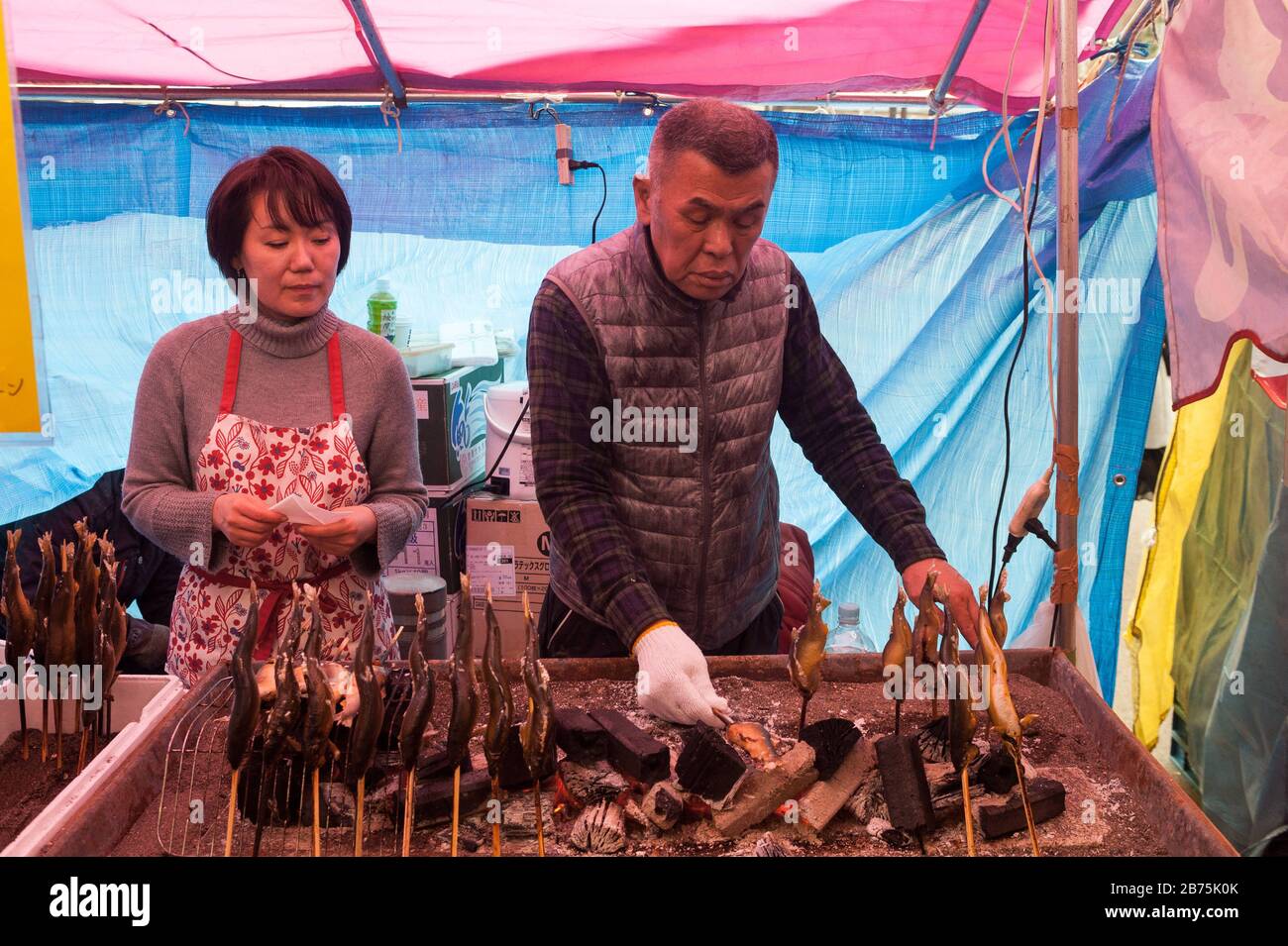 31.12.2017, Tokyo, Japon, Asie - un homme prépare des brochettes de poisson fraîchement rôties sur un stand de rue dans le quartier chibuya de Tokyo. [traduction automatique] Banque D'Images