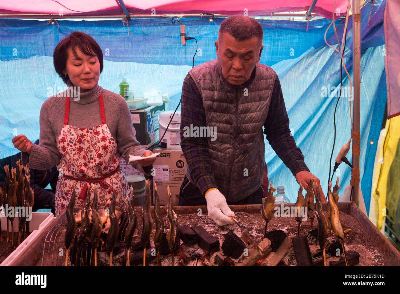 31.12.2017, Tokyo, Japon, Asie - un homme prépare des brochettes de poisson fraîchement rôties sur un stand de rue dans le quartier chibuya de Tokyo. [traduction automatique] Banque D'Images