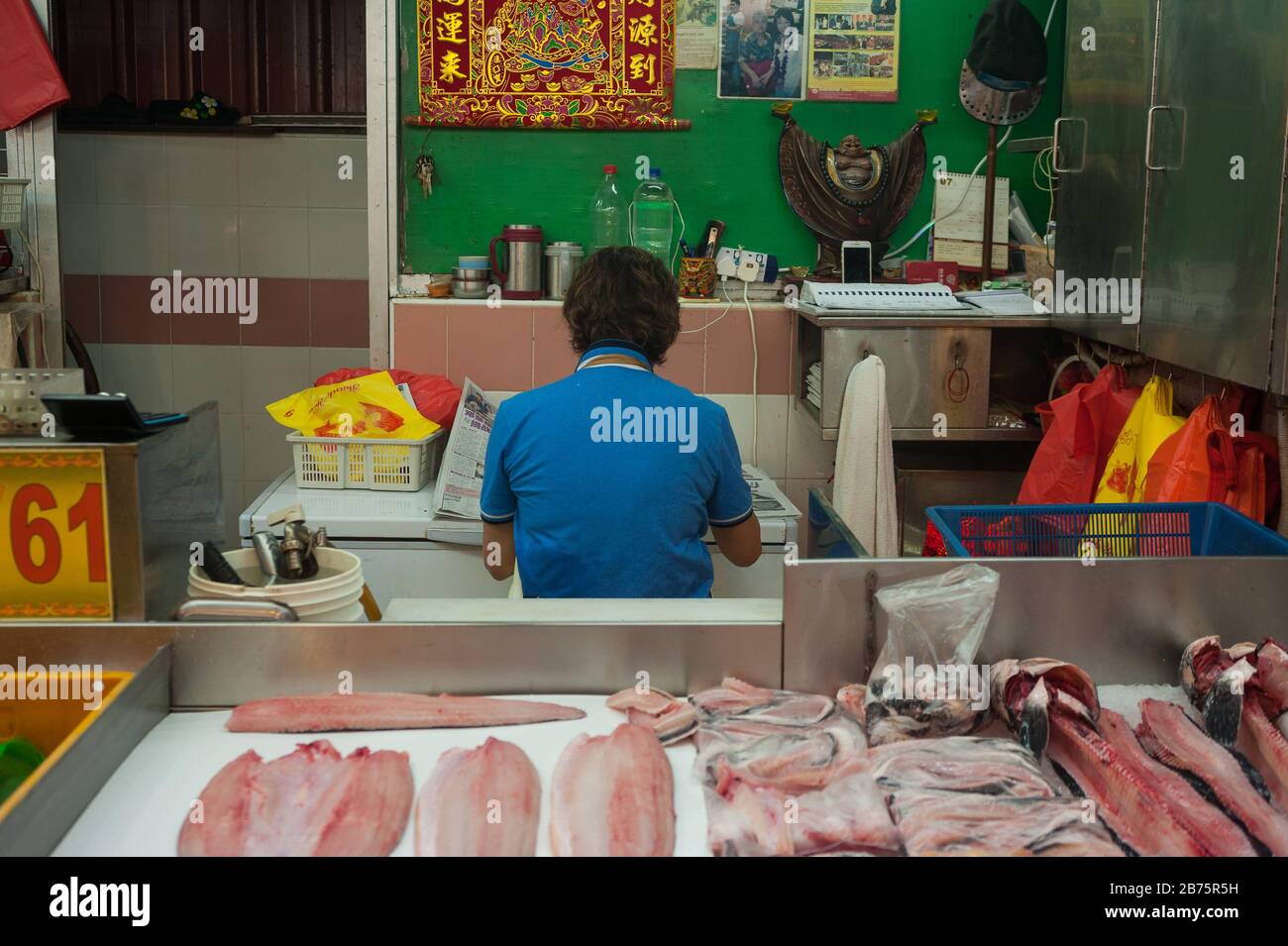 27.07.2017, Singapour, République de Singapour, Asie - un vendeur de poissons du marché chinois prend une pause et lit le journal tout en mangeant. [traduction automatique] Banque D'Images