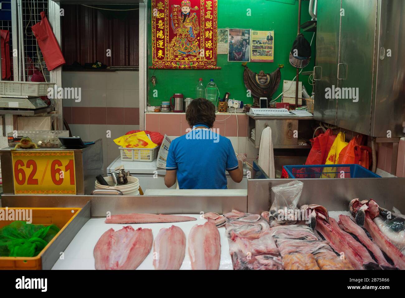 27.07.2017, Singapour, République de Singapour, Asie - un vendeur de poissons du marché chinois prend une pause et lit le journal tout en mangeant. [traduction automatique] Banque D'Images