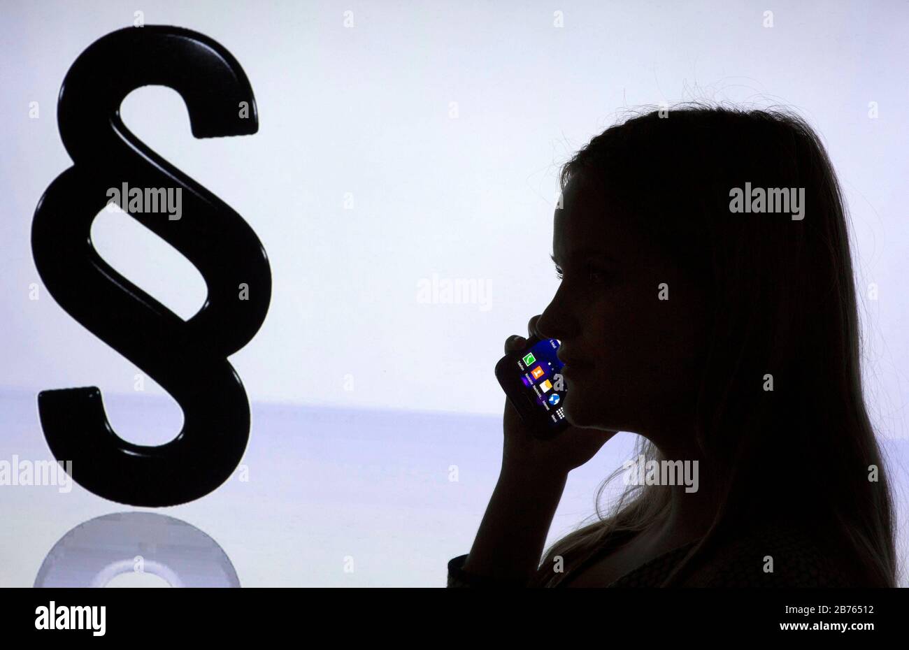 La silhouette d'une femme avec un smartphone dans sa main peut être vue devant un logo Paragrapen, le 12.01.2016. Consultation téléphonique en matière juridique. [traduction automatique] Banque D'Images