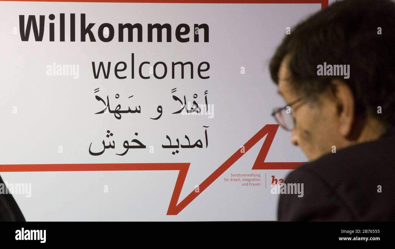 Un journaliste regarde une affiche disant "Bienvenue" en allemand, arabe et  anglais dans le premier "Bienvenue au bureau de travail" de Berlin pour les  réfugiés. Le Job point est situé dans le