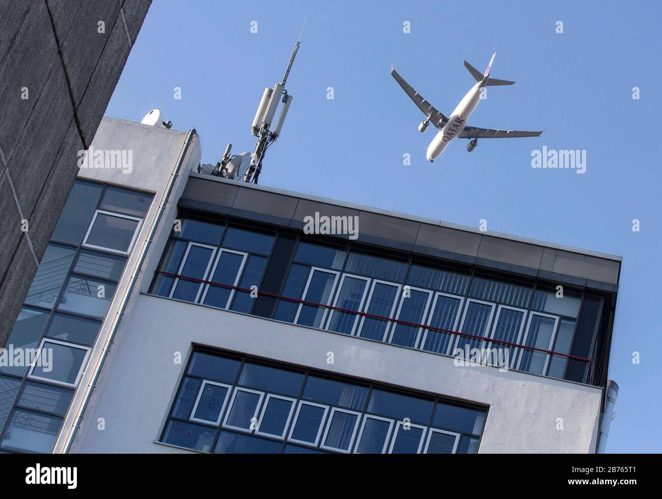 Un avion de la compagnie aérienne du Qatar survolera les maisons résidentielles et les immeubles de bureaux le 10 décembre 2015, le train d'atterrissage étant prolongé lors de l'approche d'atterrissage de l'aéroport de Berlin Tegel. [traduction automatique] Banque D'Images