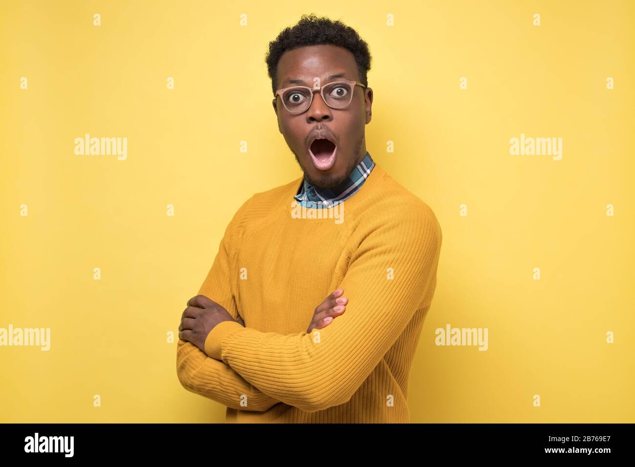 Jeune afro-américain en chandail jaune en état de choc, en gardant la bouche ouverte Banque D'Images