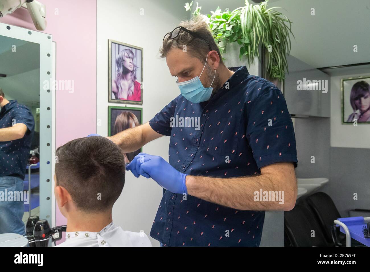 Ferrara, 13 Mars 2020. Un coiffeur travaille dans son salon de coiffure portant un masque de sécurité et des gants en raison de l'urgence du coronavirus à Ferrara, en Italie. Crédit: Filippo Rubin / Alay Live News Banque D'Images