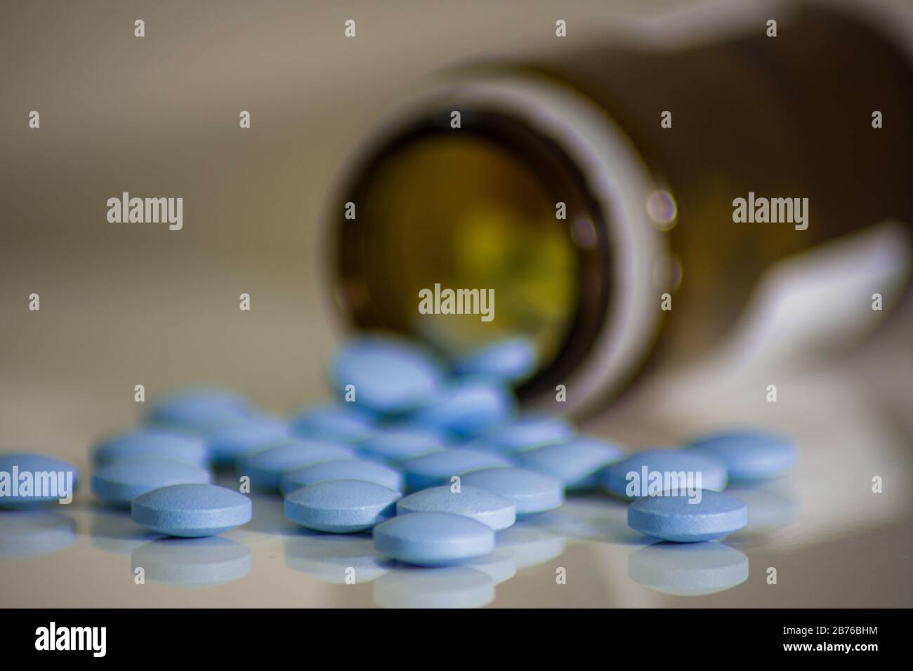 Pilules médicales bleues déversées à partir d'un verre brun, de petites comprimés aidant à la lutte contre les virus Banque D'Images