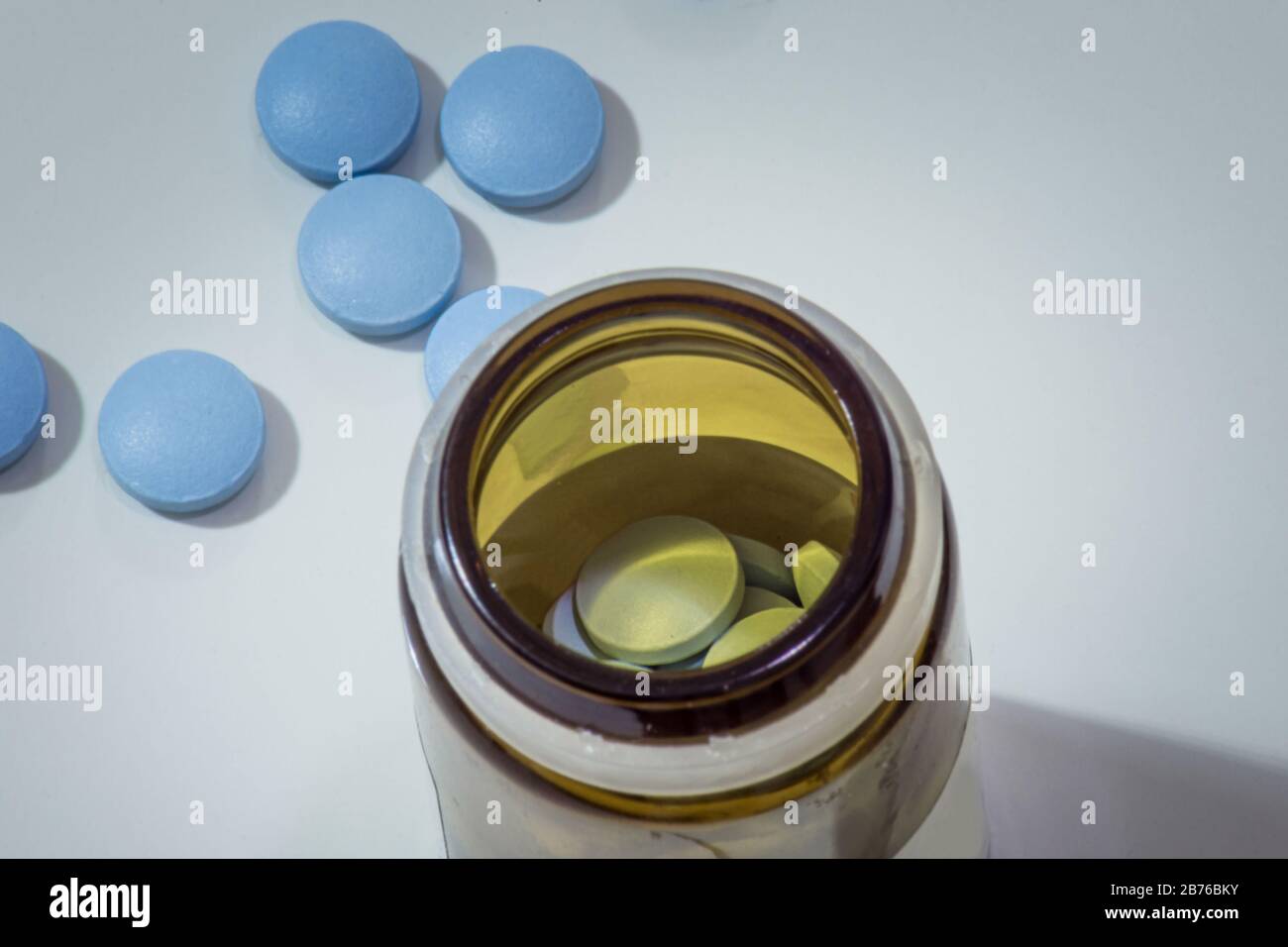 Pilules médicales bleues dans un petit pot et sur la table Banque D'Images