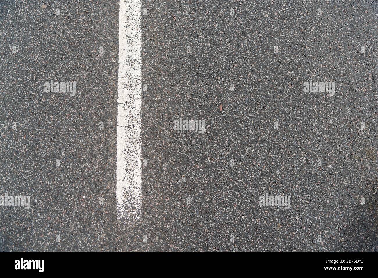 Texture de la route asphaltée, fond de Grainy, petites pierres hachées noir et gris avec une route de ligne de guidage blanche Banque D'Images