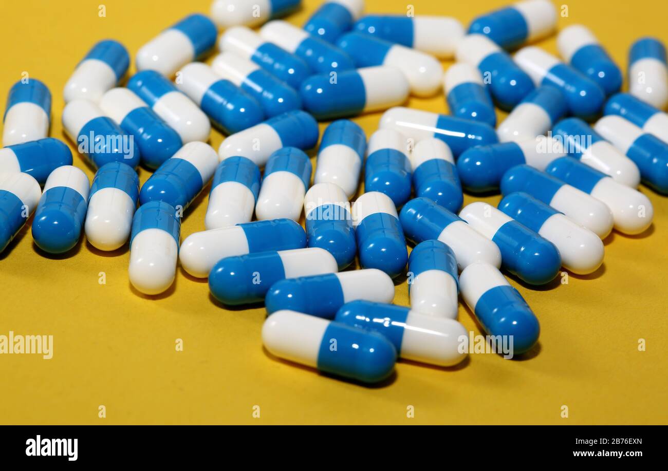 Comprimés de comprimés de comprimés de comprimés de couleur bleue et blanche gélules médicaments macro de médecine gros plan isolé sur fond jaune. Banque D'Images