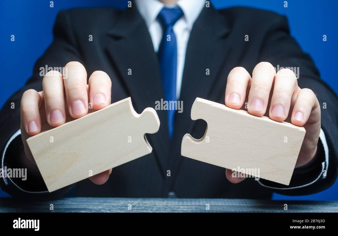 Homme d'affaires tient en mains deux pièces vides du puzzle. Le processus de connexion dans un seul ensemble, assemblage, création de nouveau. Gestion d'entreprise Banque D'Images