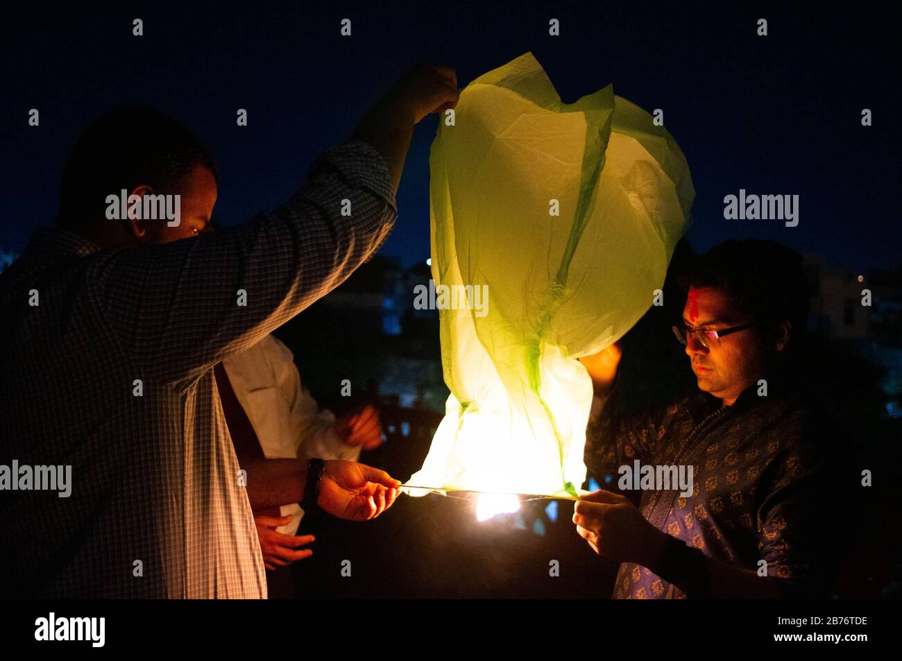 Jaipur Inde, Circa 2020 - Photographie de personnes tenant une lanterne jaune avec les flammes montrant clairement. La lanterne du ciel est tenu par 3 personnes attendent Banque D'Images