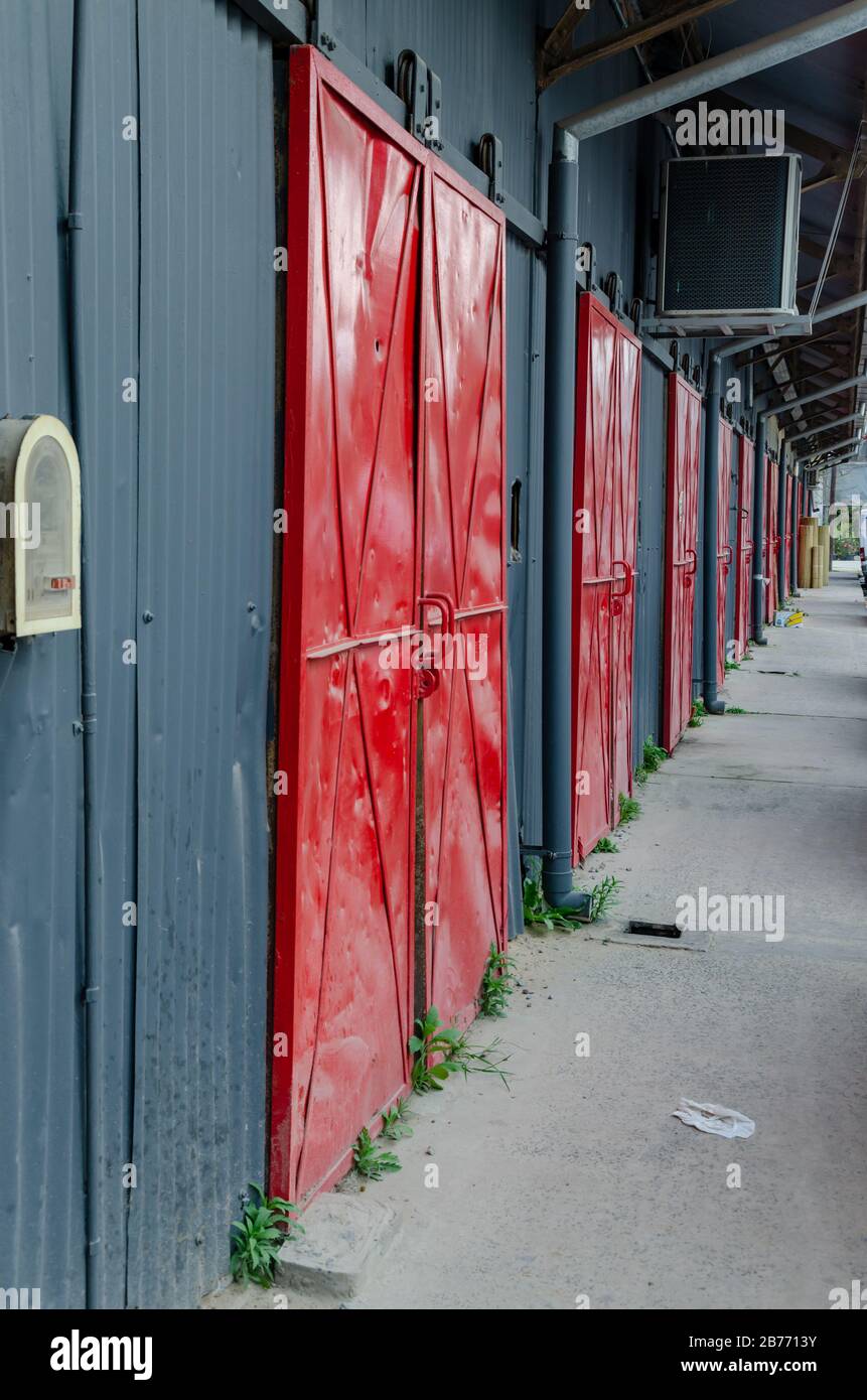 Portes rouges métalliques dans une grange de rangement avec murs gris Banque D'Images