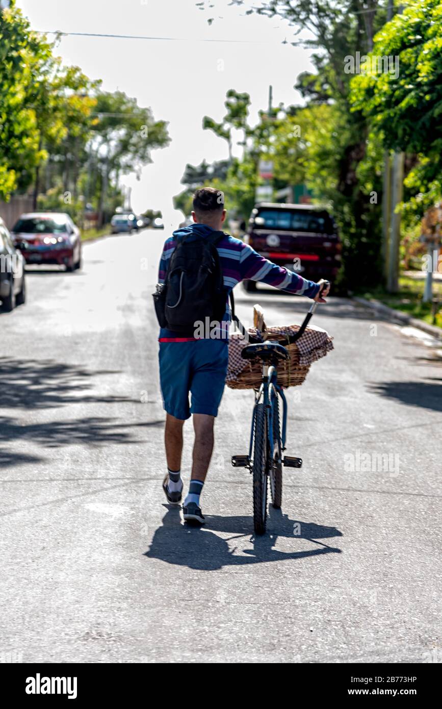 Dos d'un homme avec une bicicule et un panier en osier plein de beignets Banque D'Images