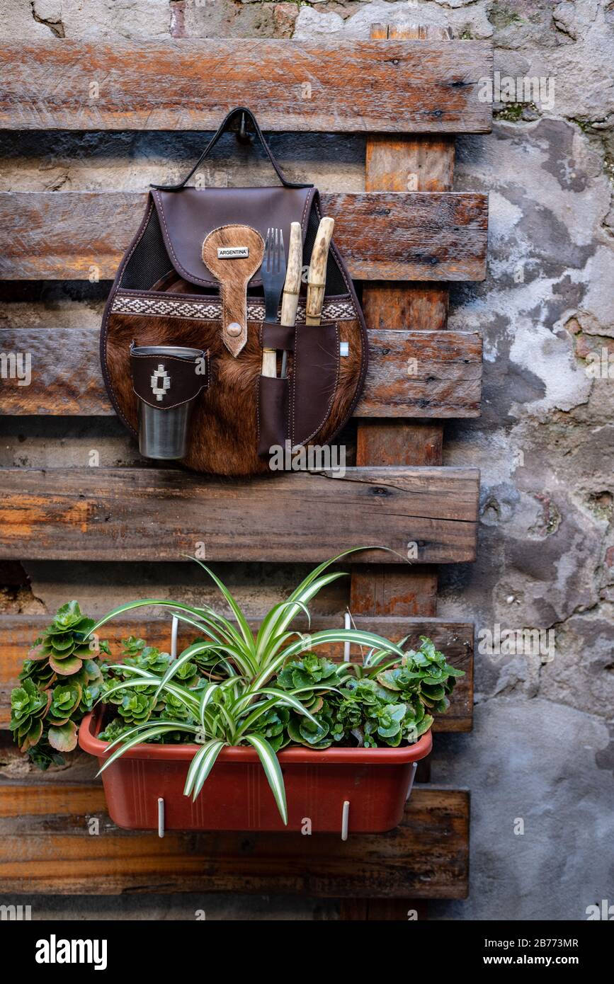 Un ensemble de couverts avec un verre et une plaque dans une enveloppe en cuir accrochée sur une palette en bois avec un pot avec des plantes sur un mur de ciment Banque D'Images