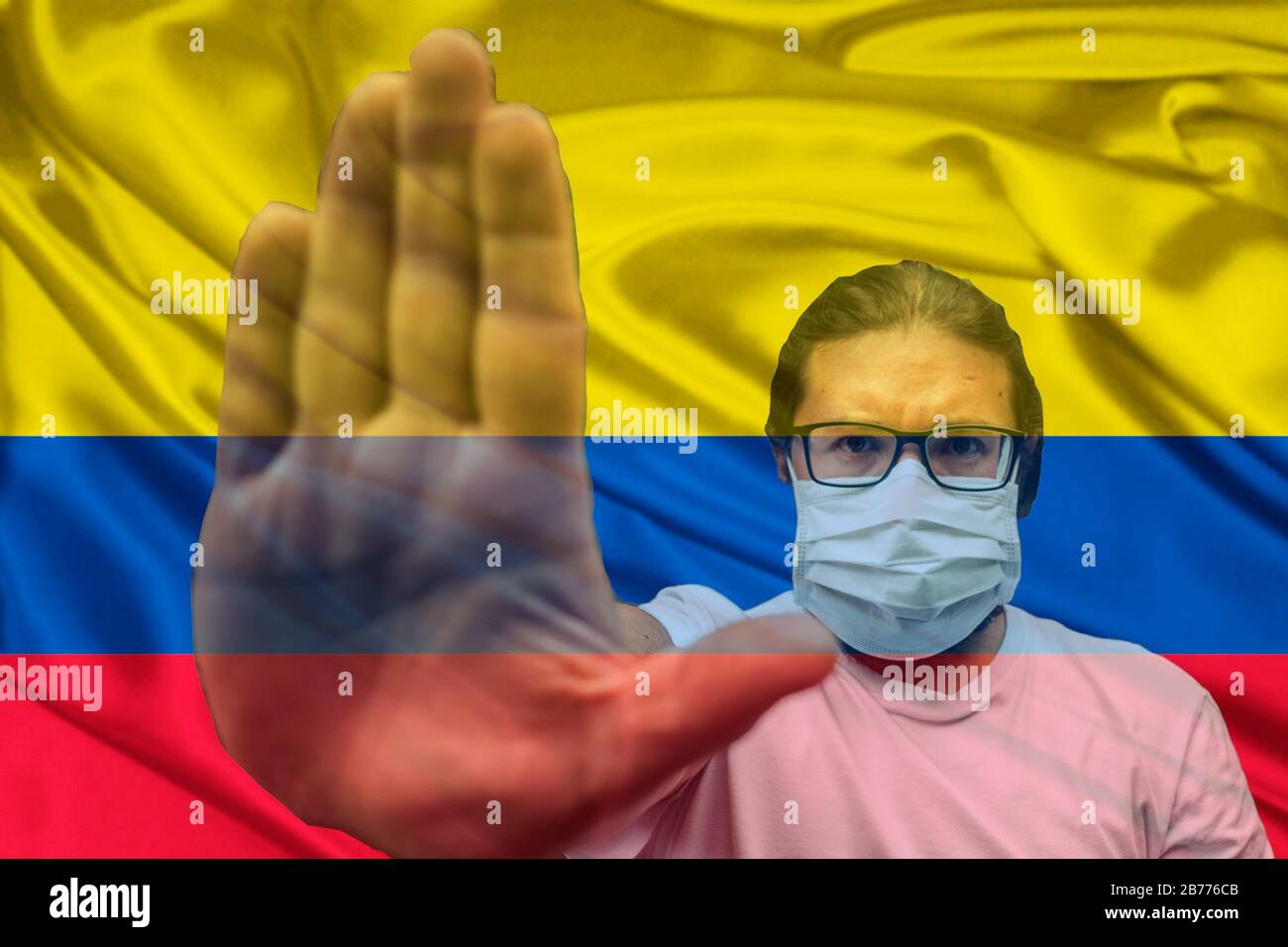 Homme portant des lunettes et un masque faisant un geste d'arrêt Sur le drapeau de la Colombie Banque D'Images