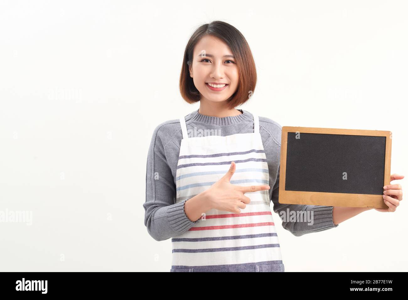 Le barista asiatique porte un point de tablier dans un menu de café blanc au comptoir avec le visage souriant Banque D'Images