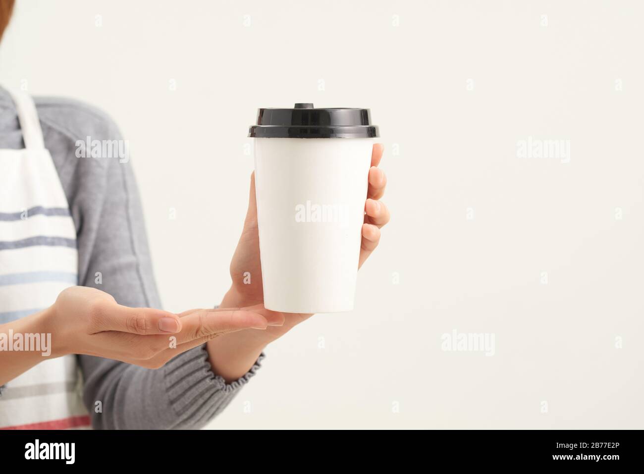 Une serveuse tenant et servant une tasse de café chaud en papier dans le café Banque D'Images