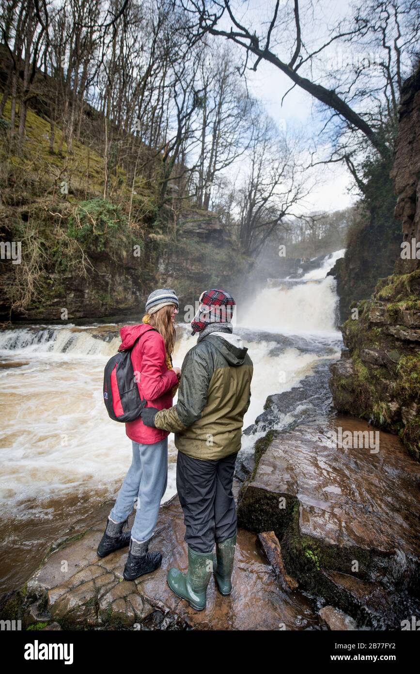 Les marcheurs marchent soigneusement sur les rives de la rivière Mellte au Sgwd Fias Clund-Gwyn tombe près de Pontnedfechan dans les Brecon Beacons, Pays de Galles, Royaume-Uni Banque D'Images