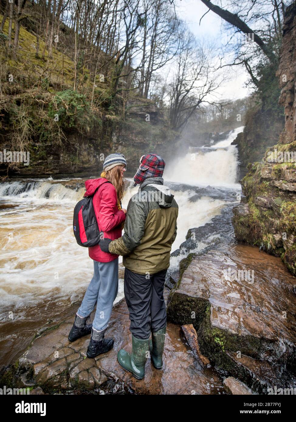 Les marcheurs marchent soigneusement sur les rives de la rivière Mellte au Sgwd Fias Clund-Gwyn tombe près de Pontnedfechan dans les Brecon Beacons, Pays de Galles, Royaume-Uni Banque D'Images