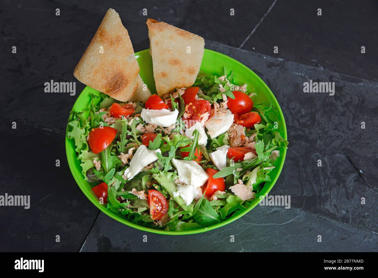 Salade fraîche mélangée avec petites tomates tranchées, fromage mozzarella et tranches de pain plat - photo studio horizontale Banque D'Images