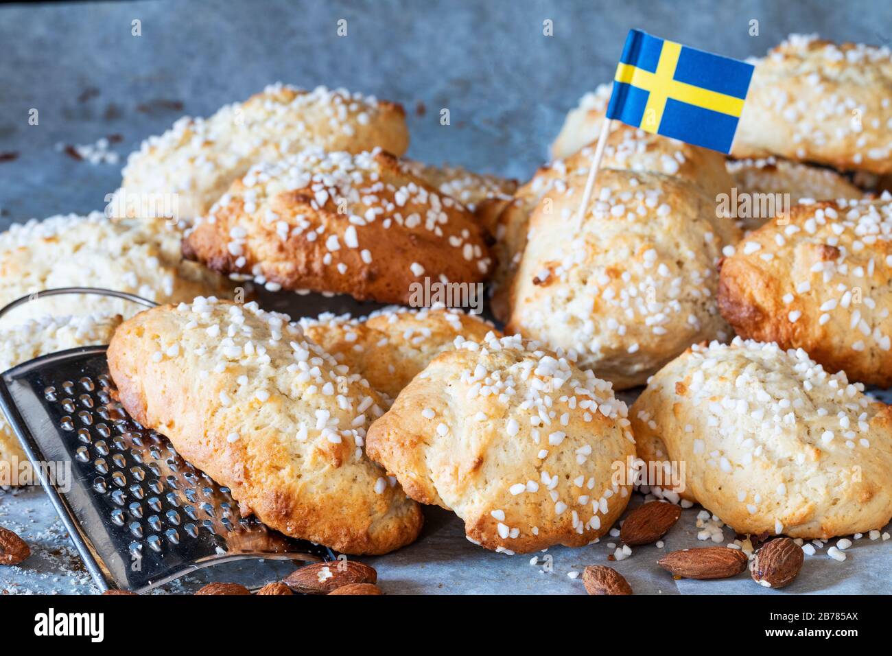 Fika suédoise, biscuits suédois aux amandes molles mandelkubb avec un drapeau suédois. Il y a un râpe et des amandes montées autour des petits pains. Banque D'Images