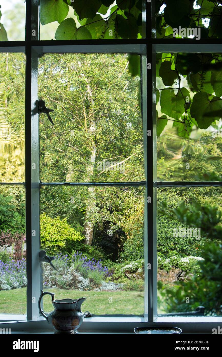 Vue encadrée à travers une fenêtre de style cottage à une belle jardin d'été Banque D'Images