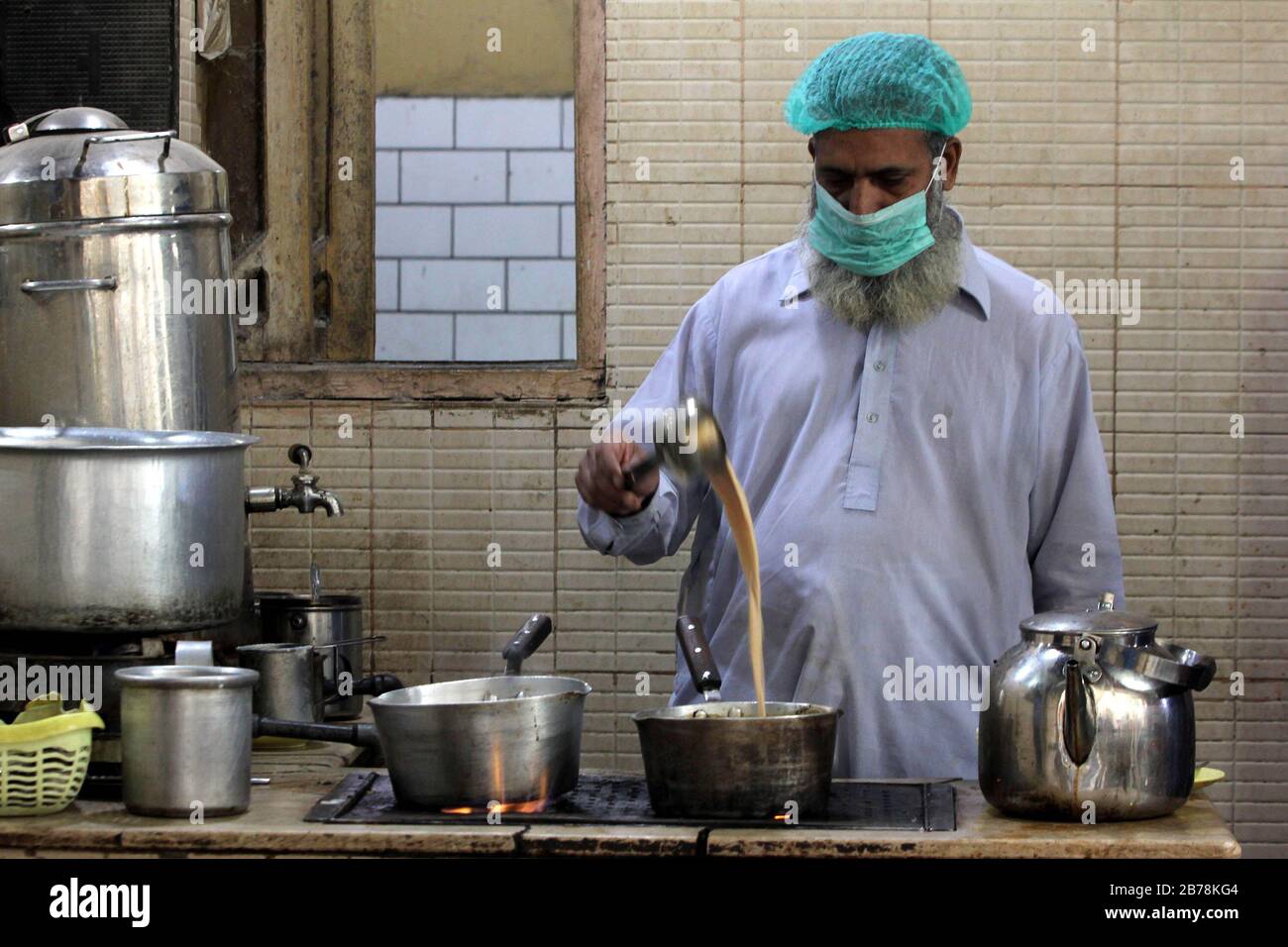 (200314) -- KARACHI, le 14 mars 2020 (Xinhua) -- un homme portant un masque de visage prépare du thé dans un restaurant dans la ville portuaire pakistanaise méridionale de Karachi, le 14 mars 2020. Le gouvernement du Pakistan a annoncé de mettre à niveau ses mesures contre COVID-19 dans tout le pays après que 28 personnes ont testé le virus positif au cours des 17 derniers jours, a déclaré l'adjoint spécial au Premier ministre de la Santé Zafar Mirza aux médias ici vendredi soir. Le pays a interdit toutes sortes de rassemblements publics, y compris des festivals sportifs et culturels, des rassemblements récréatifs dans les cinémas et les théâtres, des cérémonies de mariage à hal Banque D'Images